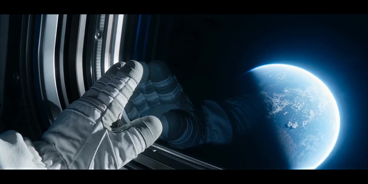 Astronaut glove against the window, Earth beyond